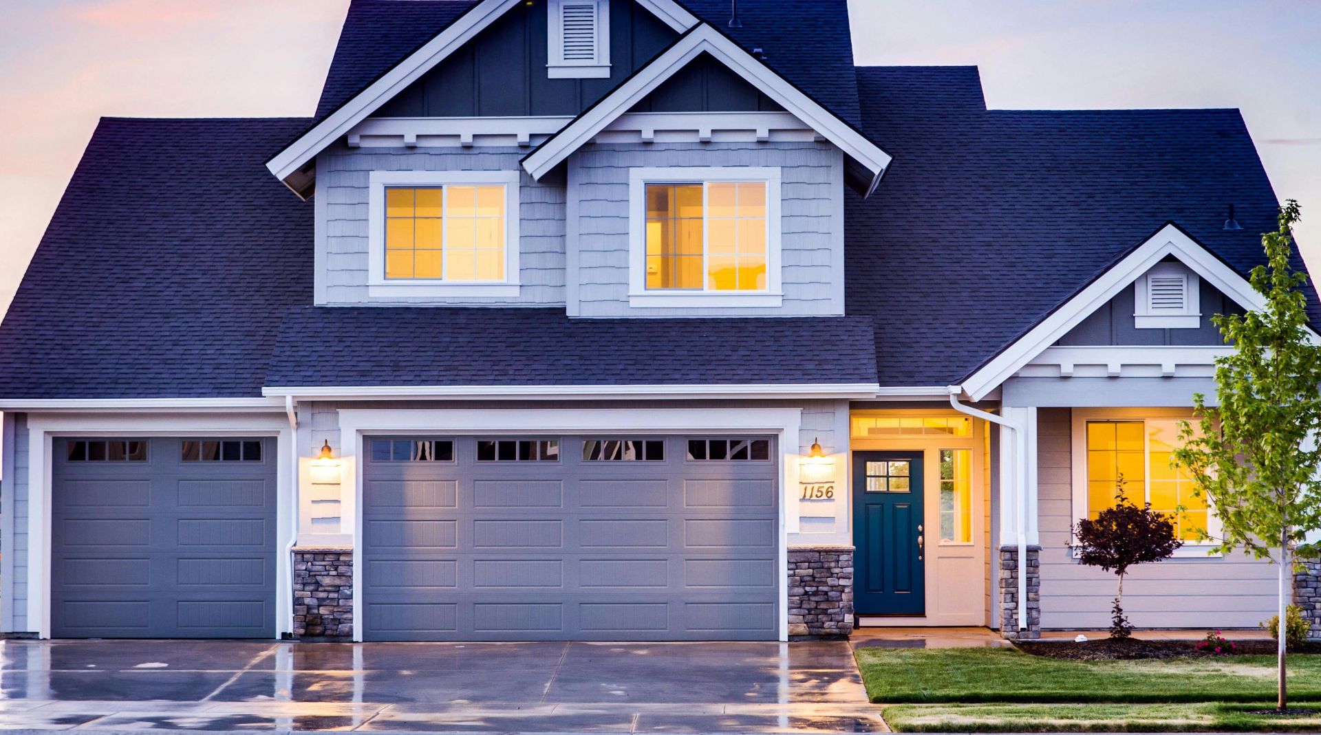 Beautiful two-story house with illuminated windows and garage at dusk.