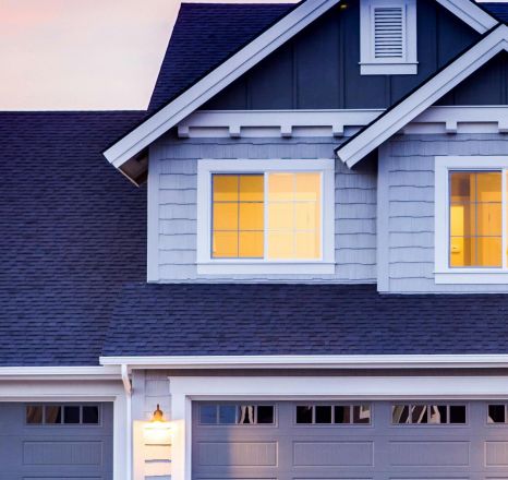 Beautiful two-story house with illuminated windows and garage at dusk.