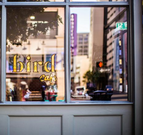 A cozy café window reflecting a bustling urban street scene and vibrant city life.